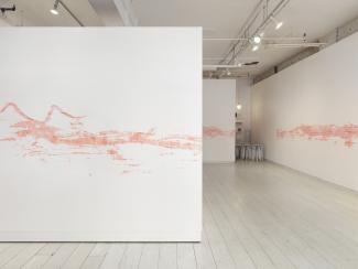 installation view of a long stencilled drawing in pink chalk