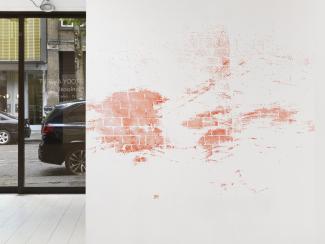 A wall with a stencilled drawing in pink chalk partially covering a view through a window
