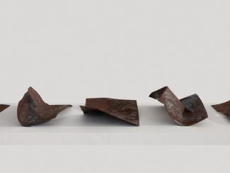 small steel plates, bent and rusted, on a white shelf