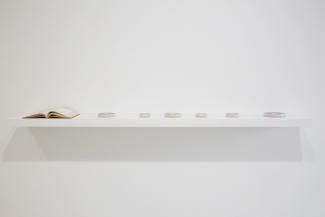 a white shelf with art objects on a white wall
