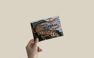 A hand holding a postcard that reads "Greetings from Summerland".