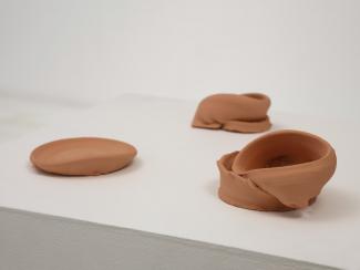 a plinth displaying three unglazed ceramic forms