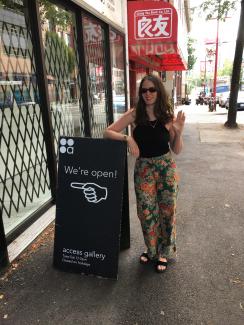 Smart and stylish woman wearing flower pants waving goodbye beside the gallery's open sign