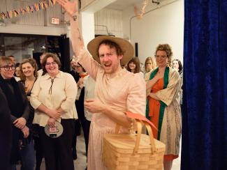 A sweet person in a pink dress with a picnic basket energizing a crowd