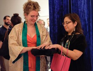 Two people touching a black rabbit fur drum