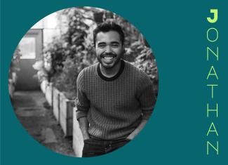 Circular image of black and white photo of Jonathan, hands in his pockets, wearing a sweater and smiling. They are standing in a greenhouse. The portrait is placed in a dark teal background with his stylized name in pale green to the right.