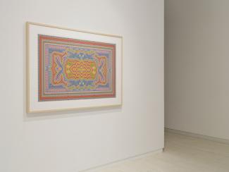 Framed colorful abstract artwork with intricate geometric patterns and vibrant hues on a white gallery wall.