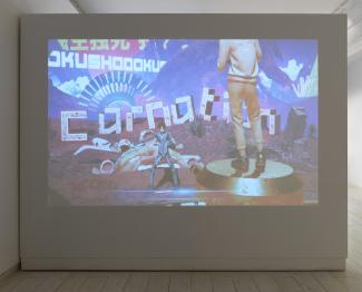 Projected digital art shows two figures in a surreal landscape. One stands on a platform, another poses in front of large, colourful text.