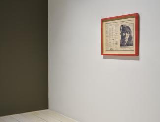 A red-framed newspaper centrefold hangs on a white wall. 